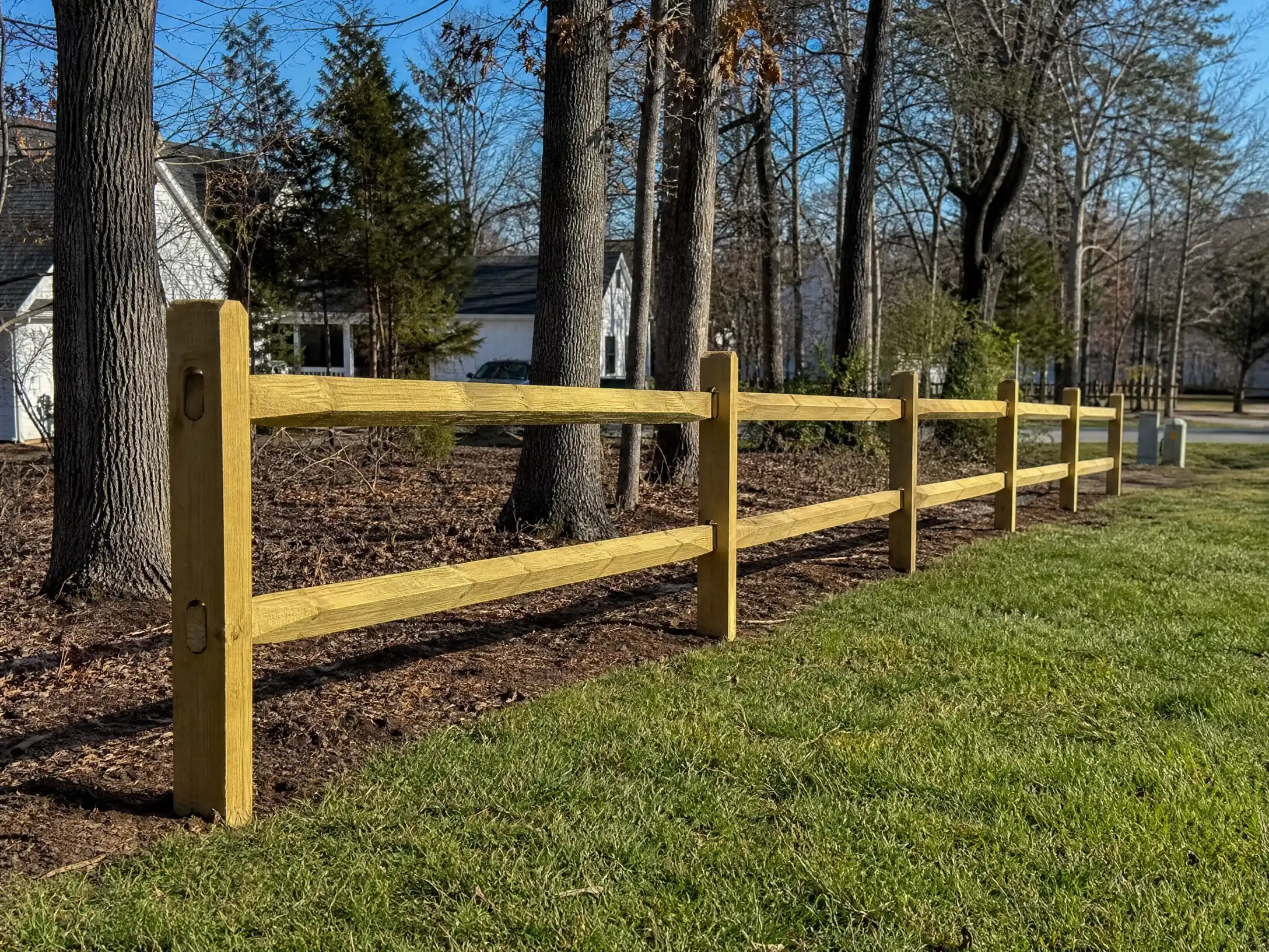 Two-rail split rail fence installed along a wooded residential property in Anne Arundel County, MD.