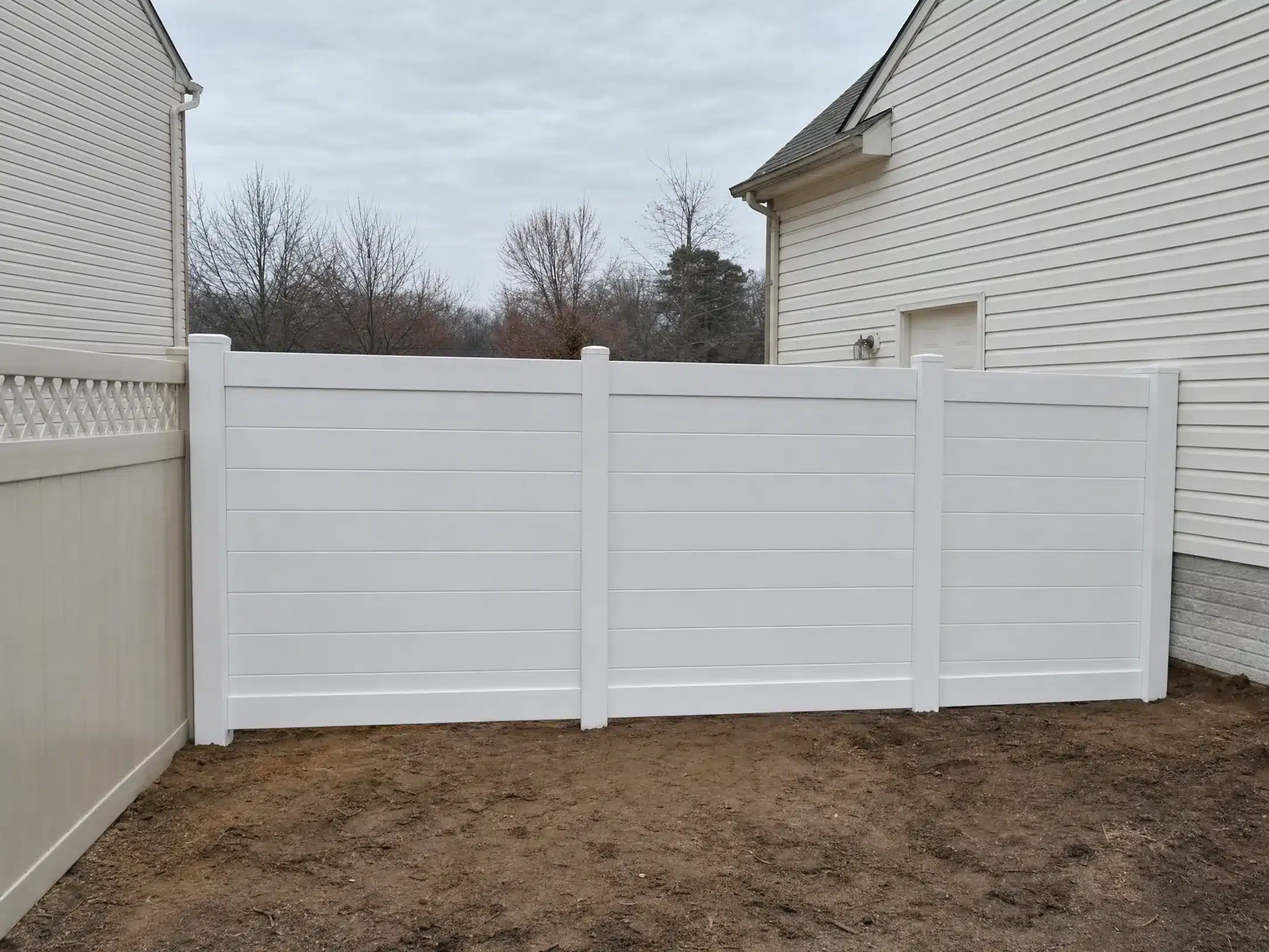 White horizontal vinyl privacy fence installed between two homes in Severna Park, MD.