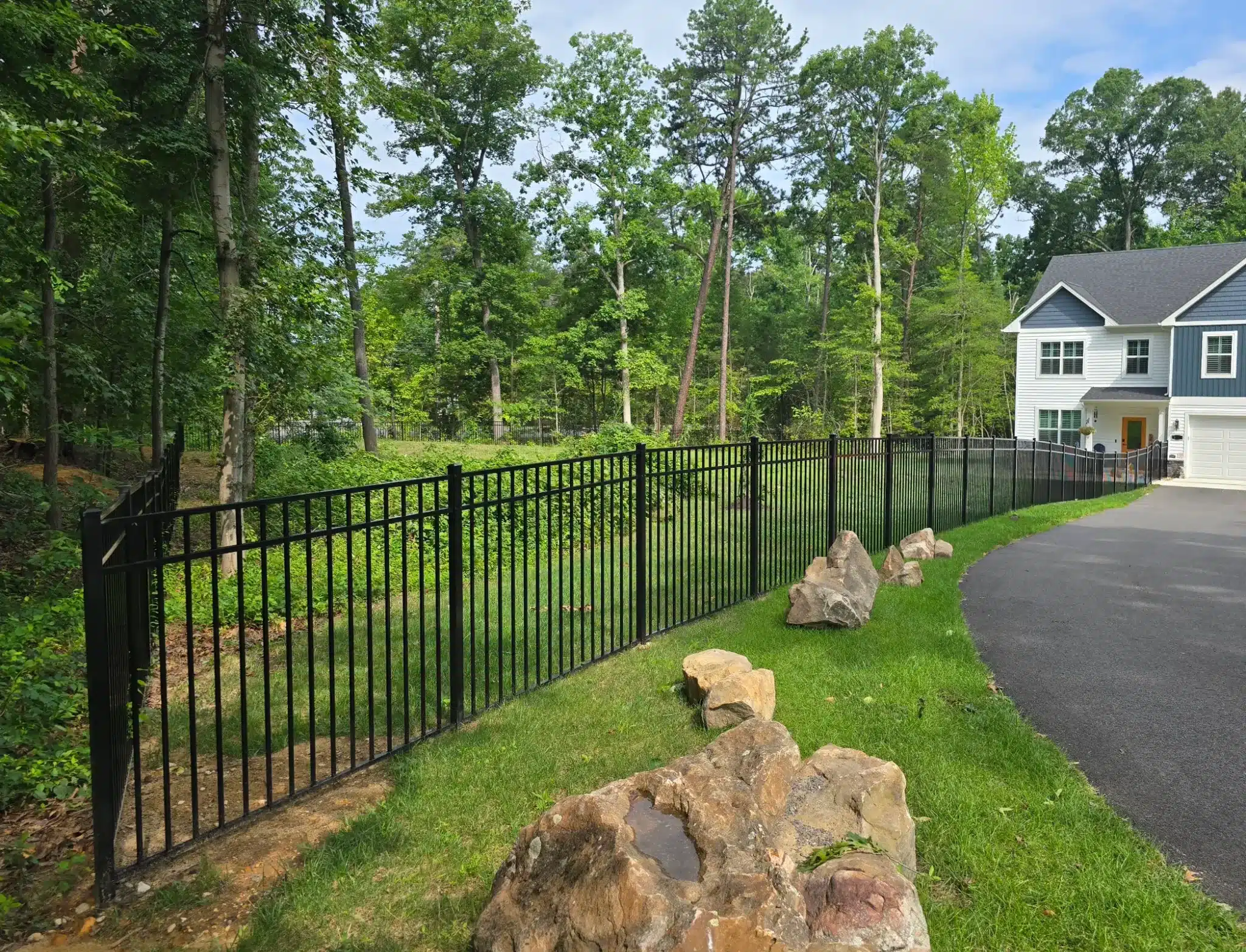 Close-up view of a black aluminum gate and fence installed beside a driveway in Pasadena, MD.