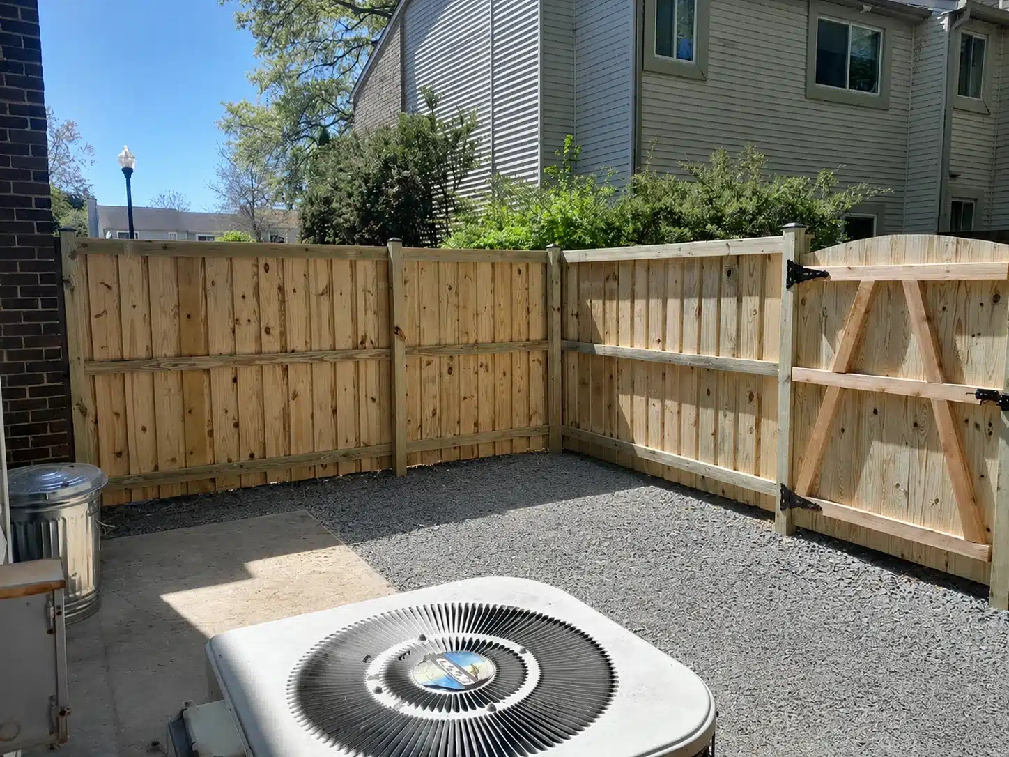 Board-on-board wood privacy fence forming a corner around a gravel side yard in Pasadena, MD.