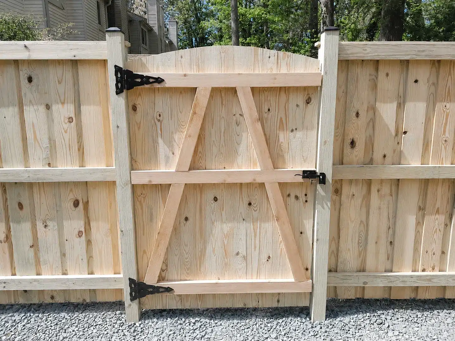 Close-up of a board-on-board wood fence gate with black hinges and latch hardware in Pasadena, MD.