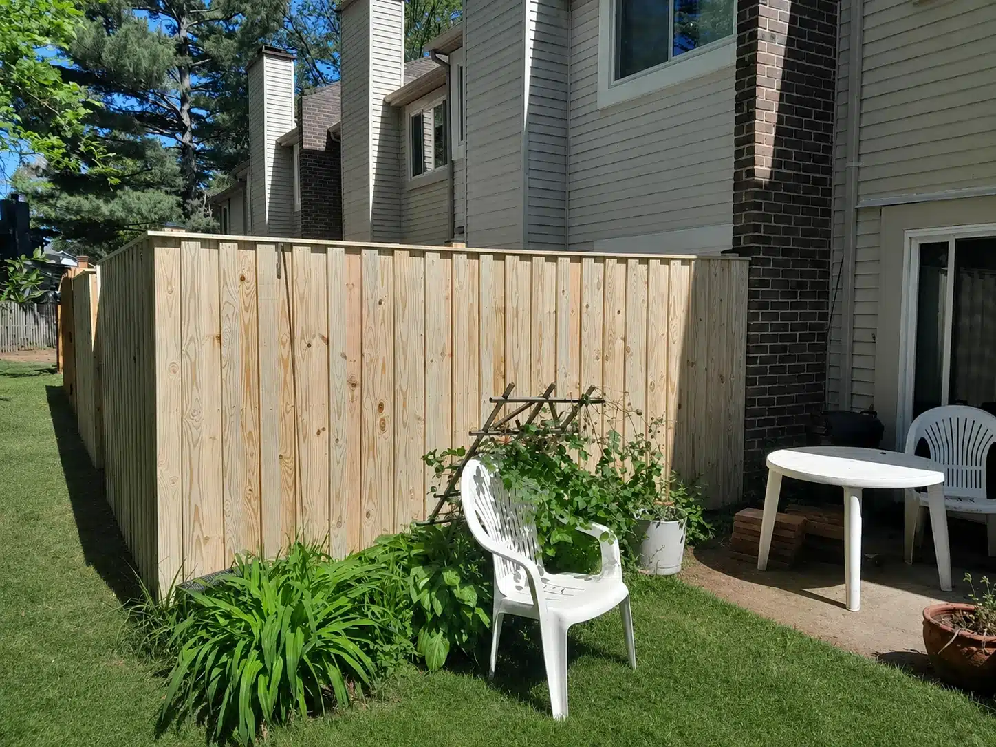Board-on-board wood privacy fence enclosing a patio side yard beside a home in Pasadena, MD.
