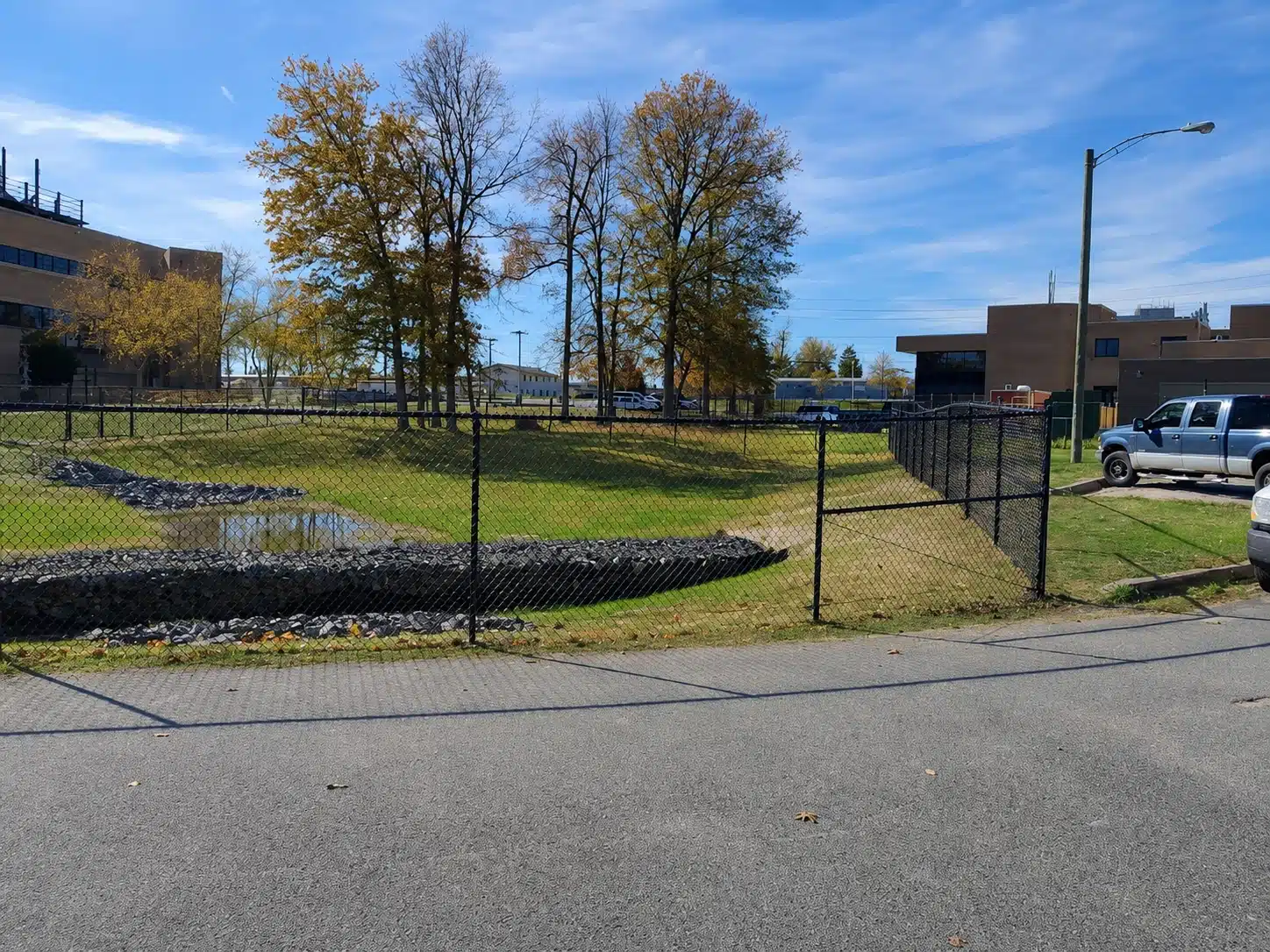 Black chain-link perimeter fence surrounding a commercial drainage basin in Severna Park.