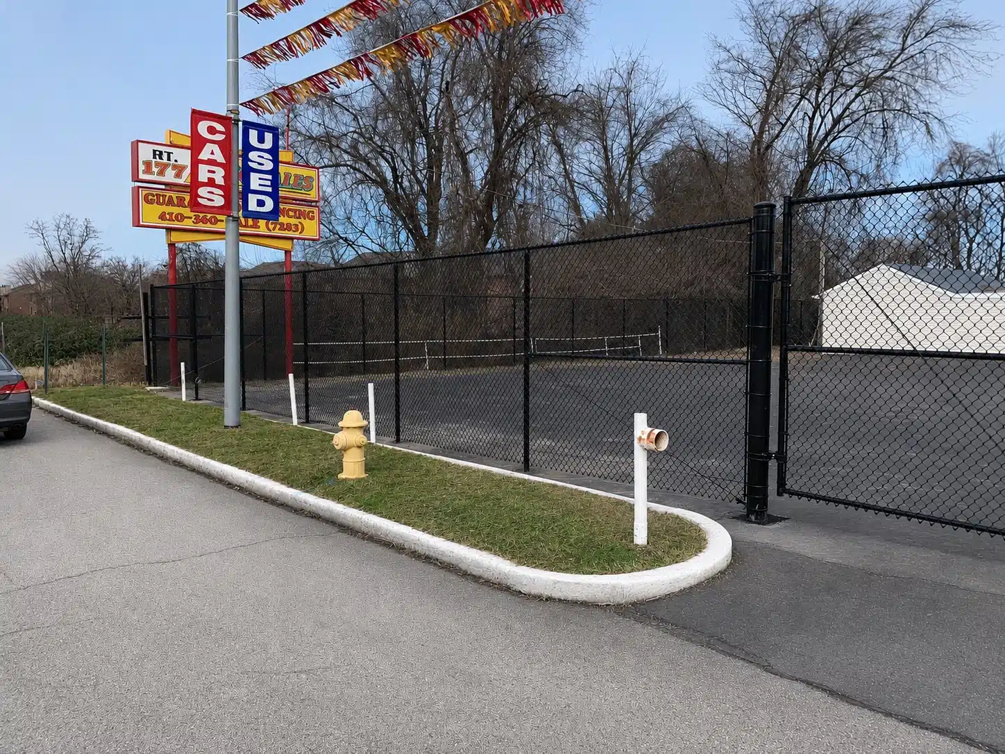 Black chain-link perimeter fence securing a used car lot in Severna Park.