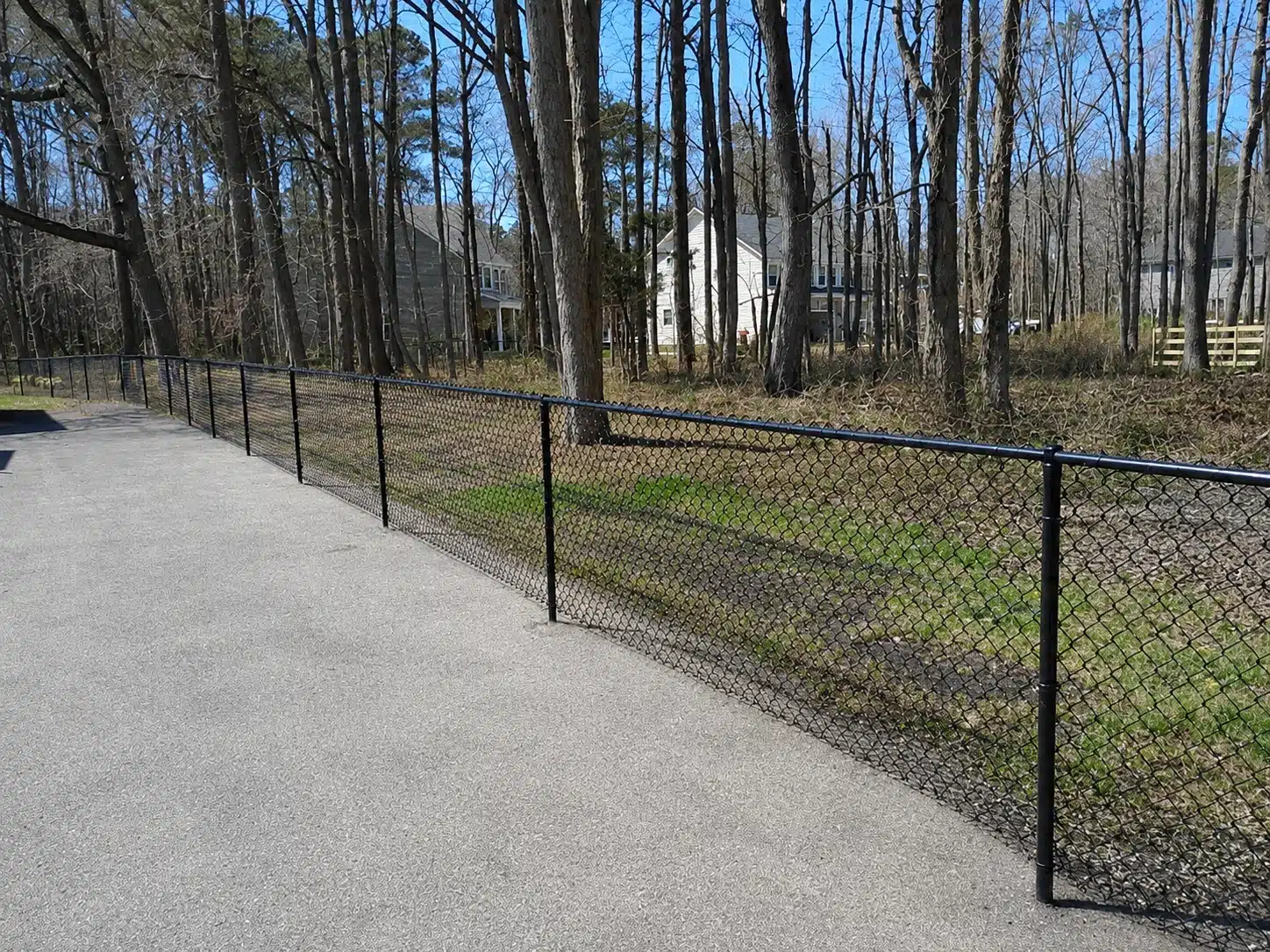 Black chain-link dog containment fence installed beside a wooded residential yard in Severna Park.