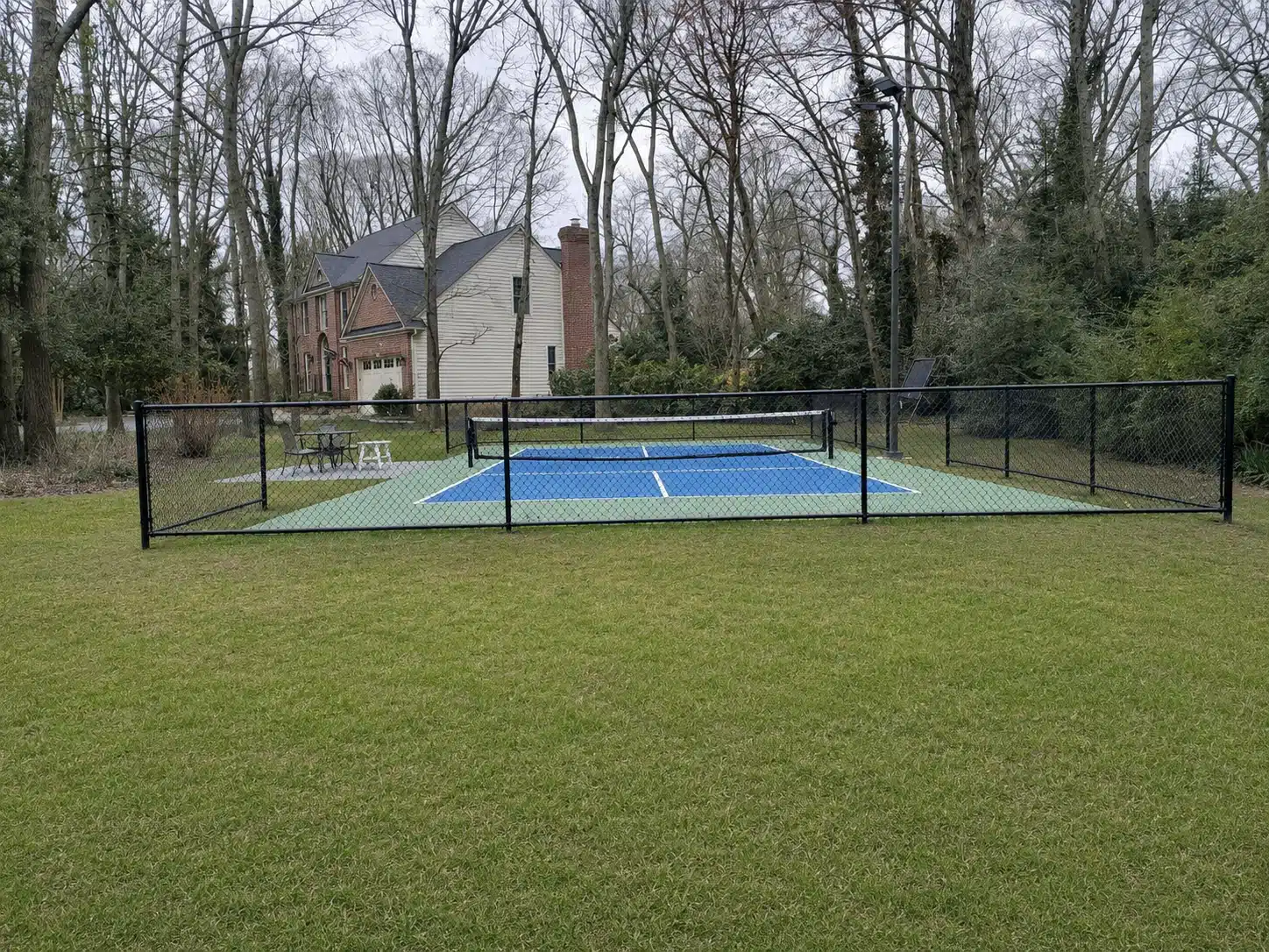 Black vinyl-coated chain-link fence enclosing a residential sports court in Severna Park.