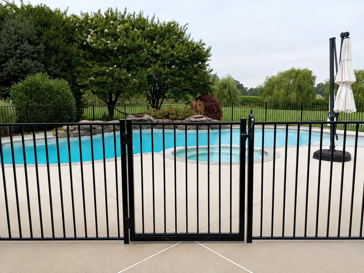 Black metal pool fence gate installed around a backyard swimming pool in Severna Park, MD.