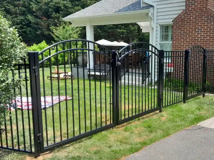 Decorative black aluminum fence and gate around a front yard with brick home landscaping.