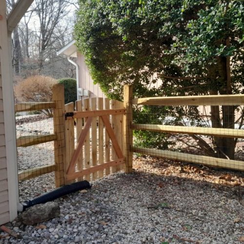 New wood split-rail fence and gate installed between homes on a sloped property in Crownsville, MD