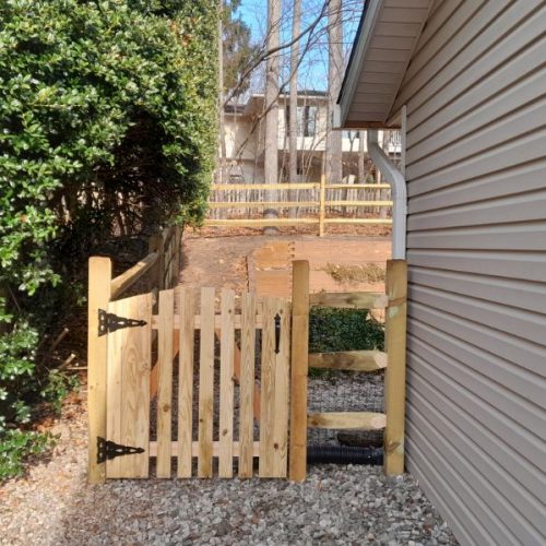 Wooden three-rail split-rail fence running along a landscaped slope in Crownsville, Maryland