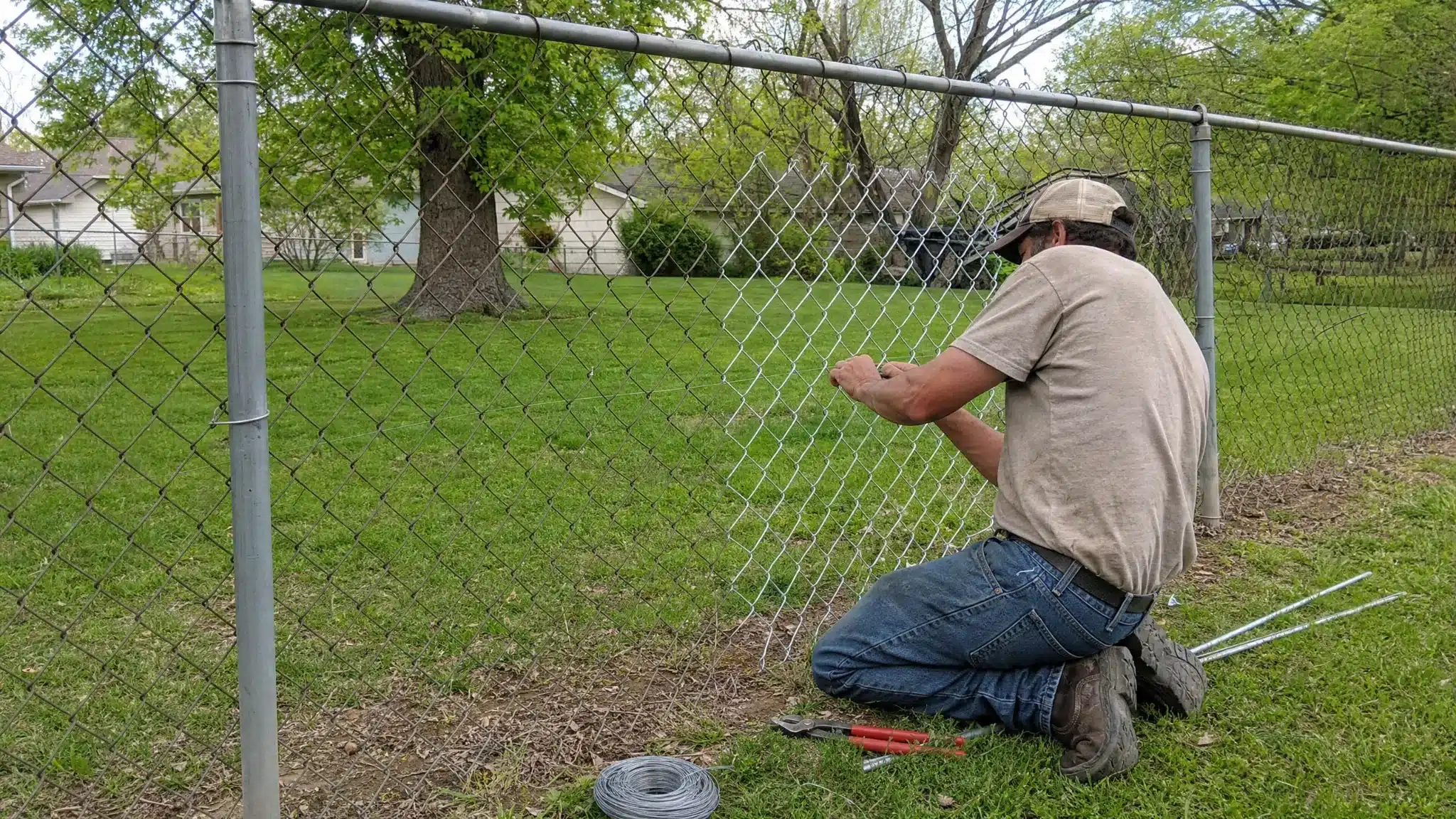 Chain link fence repair with new mesh being secured in Severna Park, MD.