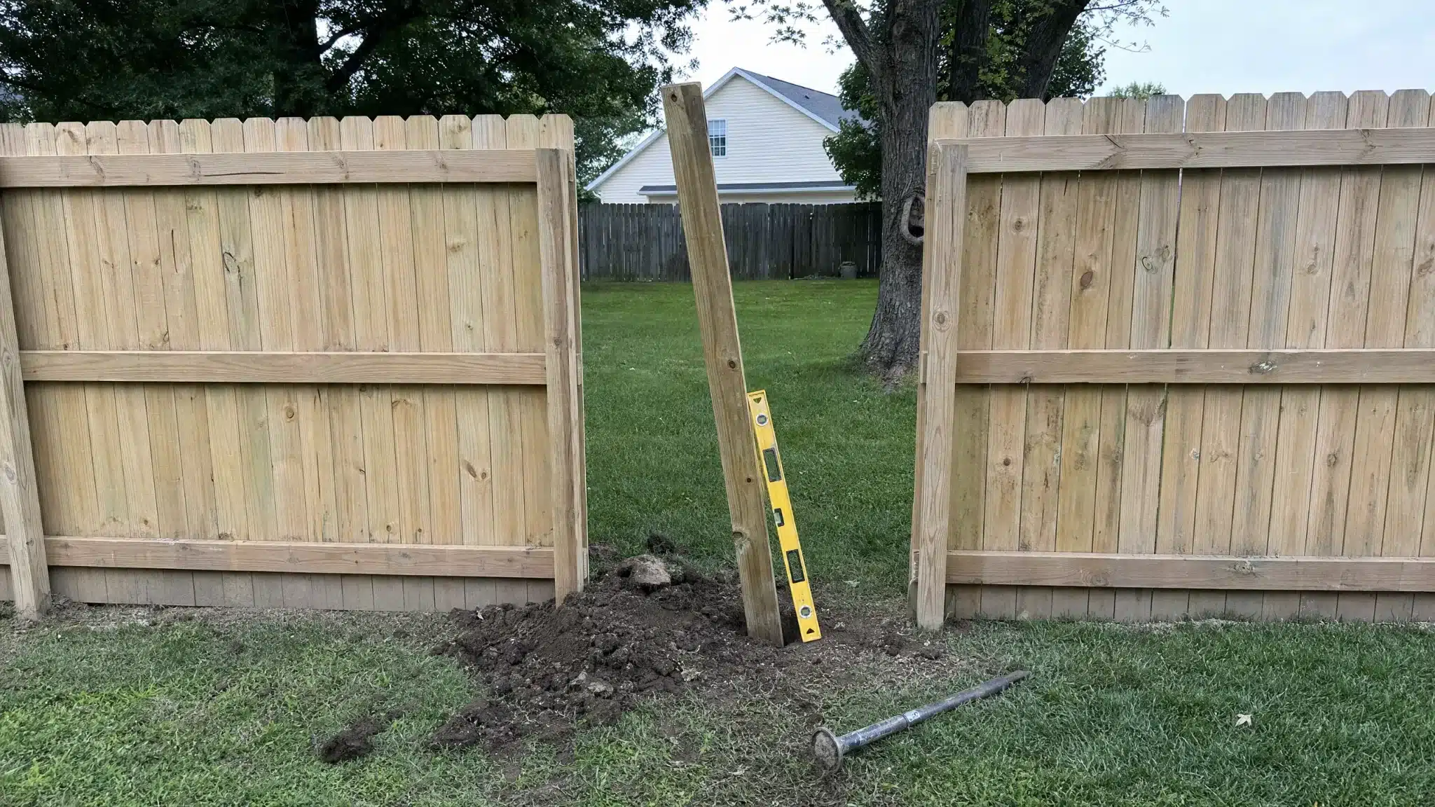 Wood fence post being reset with fresh concrete during fence repair in Severna Park, MD.