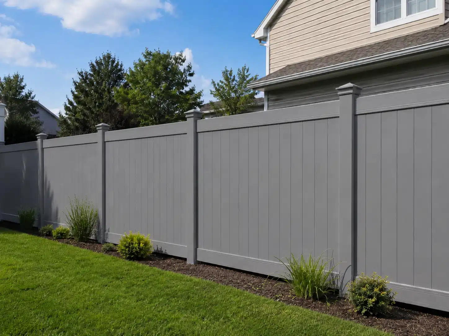 Gray vinyl fence with solid vertical panels in a residential outdoor setting