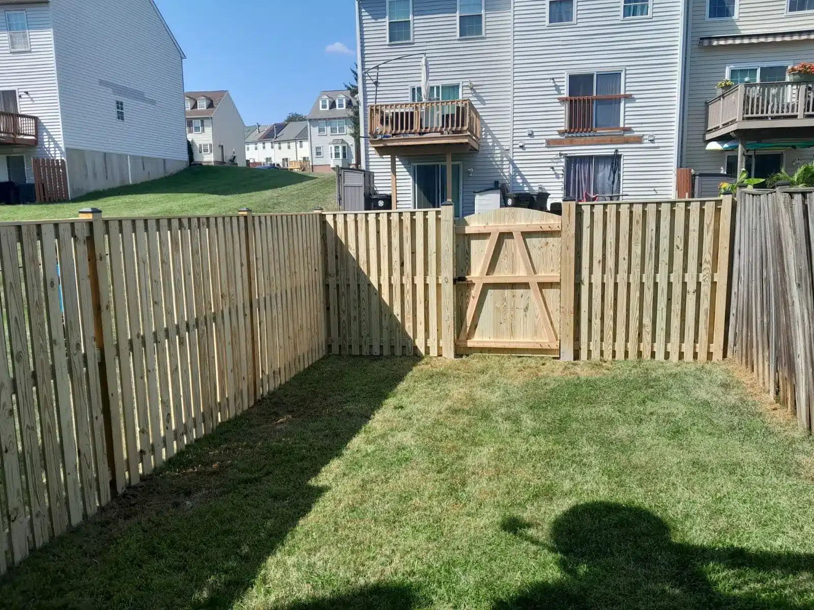 Pressure-treated wood privacy fence with gate and top rail