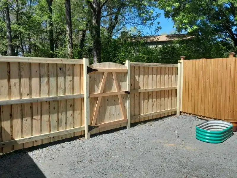 Vertical board wood fence beside tan house and porch