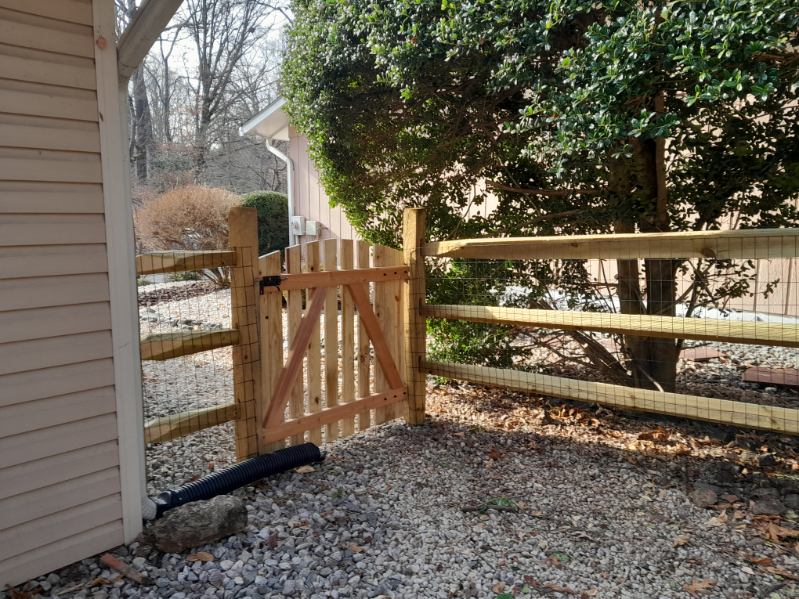 New wood split-rail fence and gate installed between homes on a sloped property in Crownsville, MD