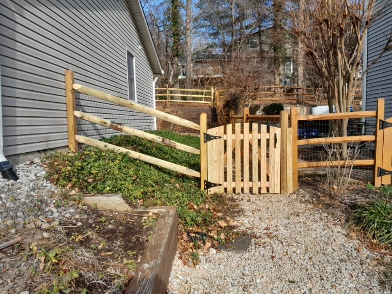Three-rail split-rail fence with welded wire installed along a terraced backyard in Crownsville, MD