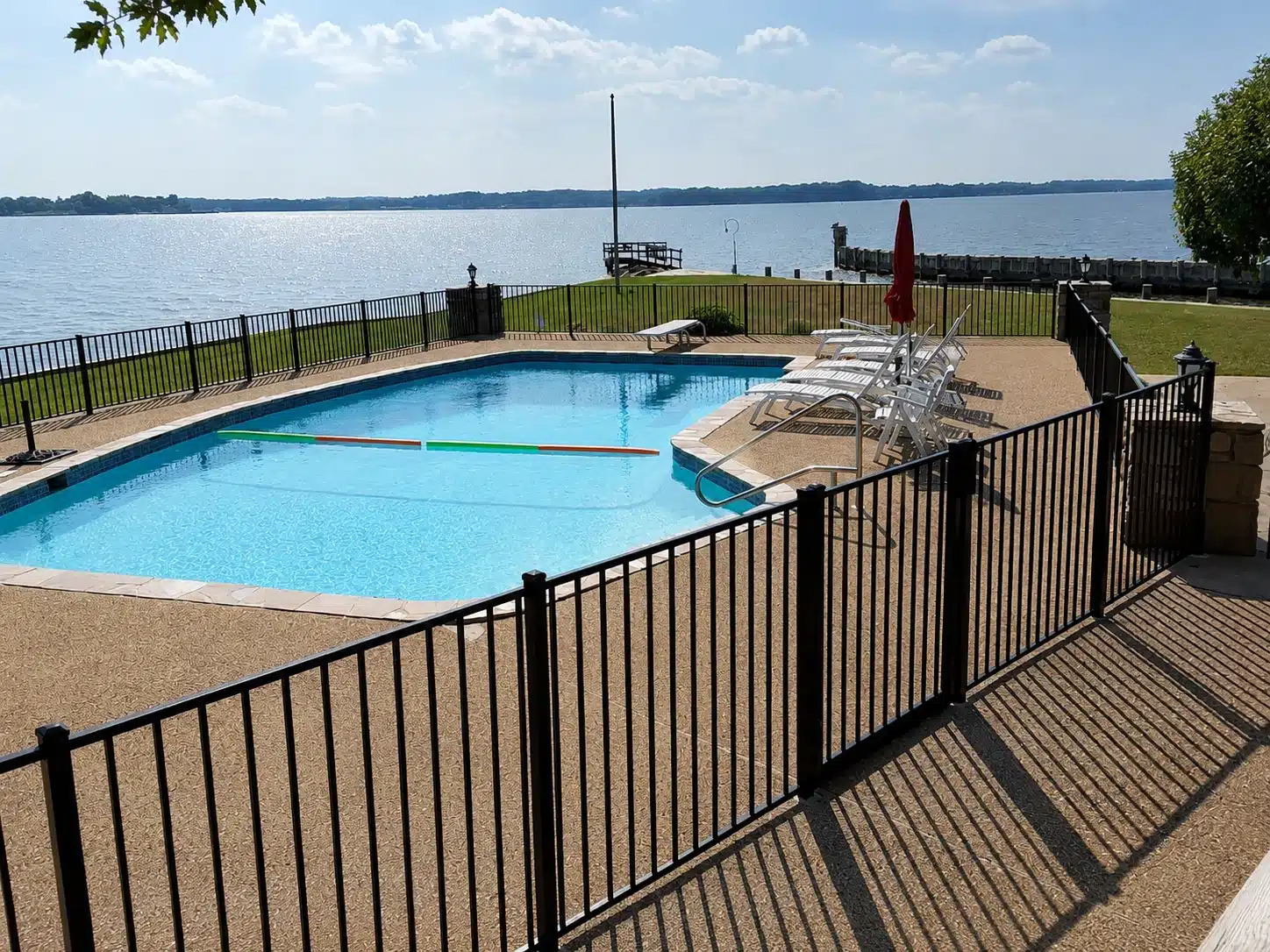 Black aluminum pool enclosure fence surrounding a waterfront swimming pool in Severna Park, Maryland.
