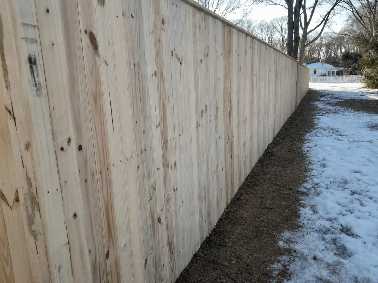 Pressure-treated board-on-board privacy fence installed along a snow-covered yard in Pasadena, MD.