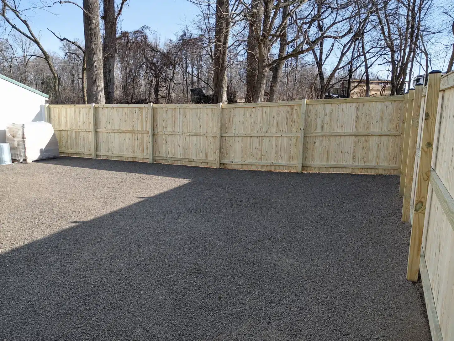 Pressure-treated stockade privacy fence surrounding a gravel-covered yard in Pasadena, MD.