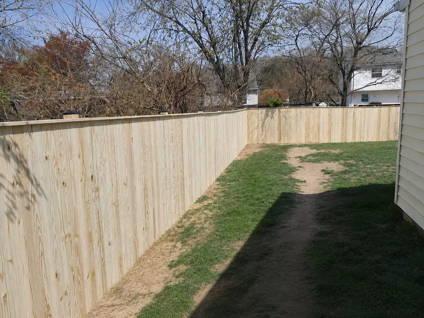 Pressure-treated stockade privacy fence with a finished top cap enclosing a backyard in Pasadena, MD.