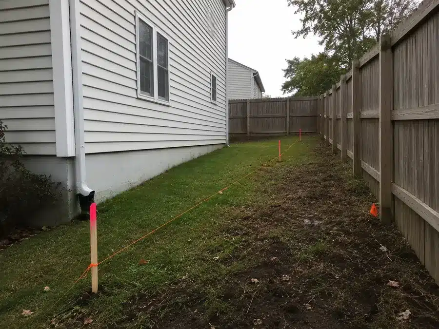 Property line stakes and string layout for a wood fence installation in Glen Burnie.