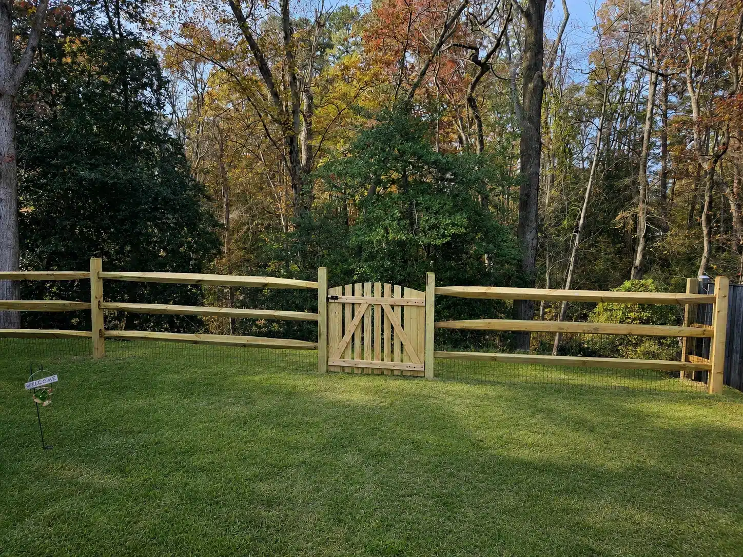 Split rail fence with wire mesh and a matching wood gate in an autumn backyard in Anne Arundel County, MD.