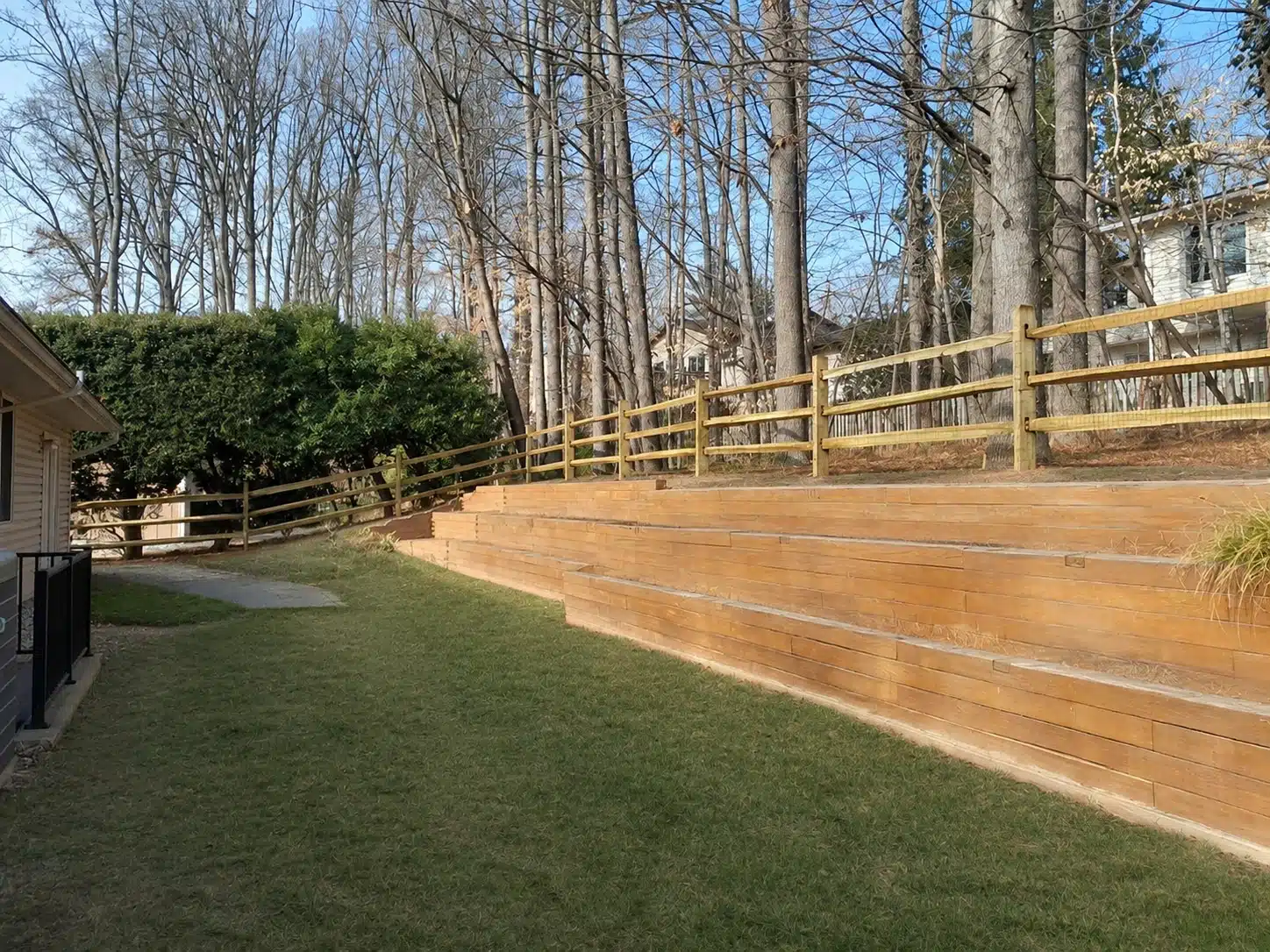 Split rail fence installed along the top of a wood retaining wall in Anne Arundel County, MD.