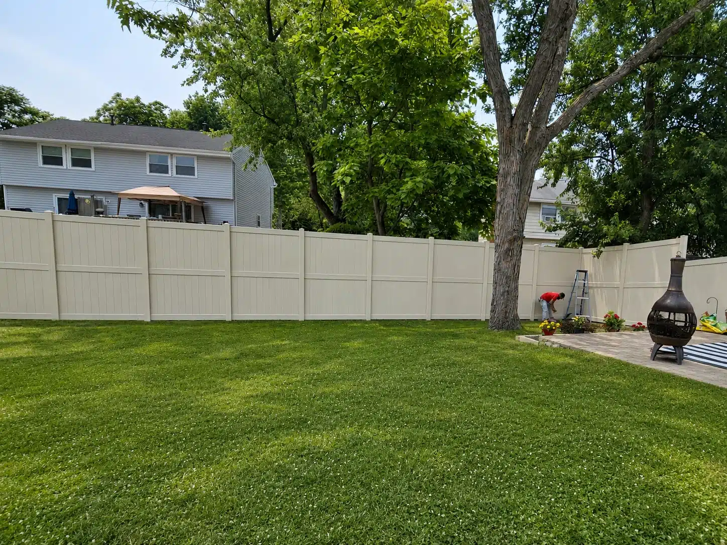 Tan vinyl privacy fence extending across a landscaped residential backyard in Pasadena, MD.