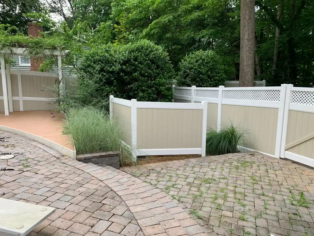 Tan and white vinyl fence with lattice top around a Maryland backyard patio with landscaping