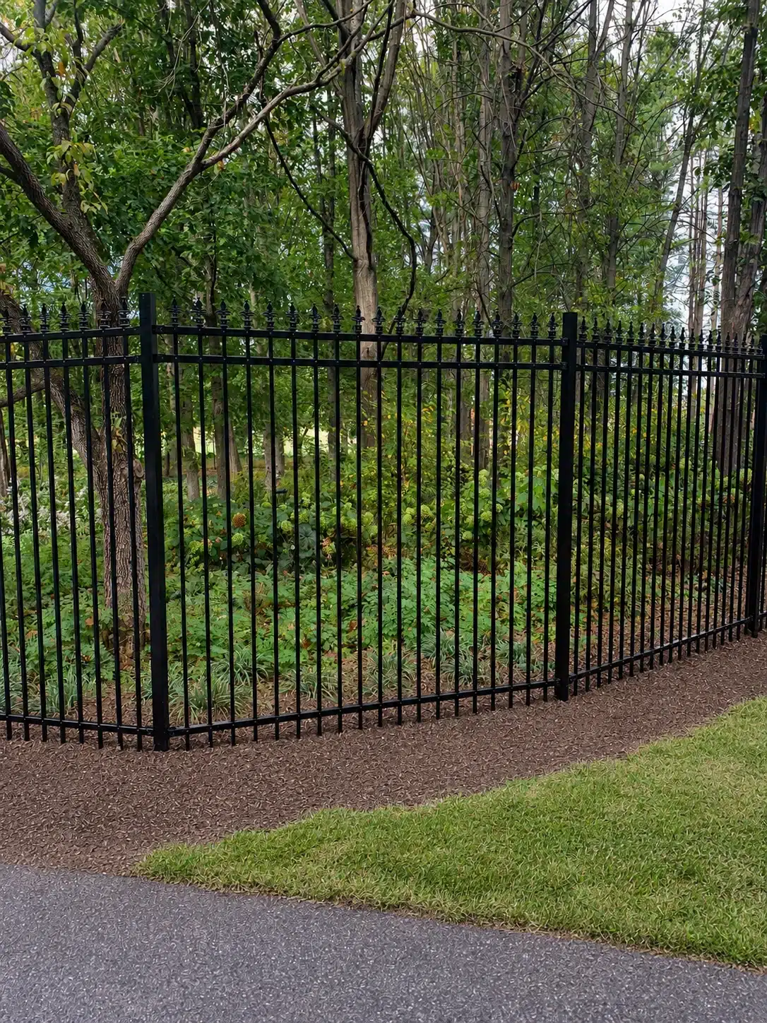 Black three-rail aluminum fence with decorative pickets installed around a wooded property in Severna Park, Maryland.