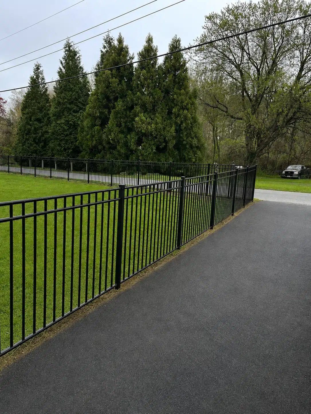 Black two-rail aluminum fence installed beside a residential driveway in Severna Park, Maryland.