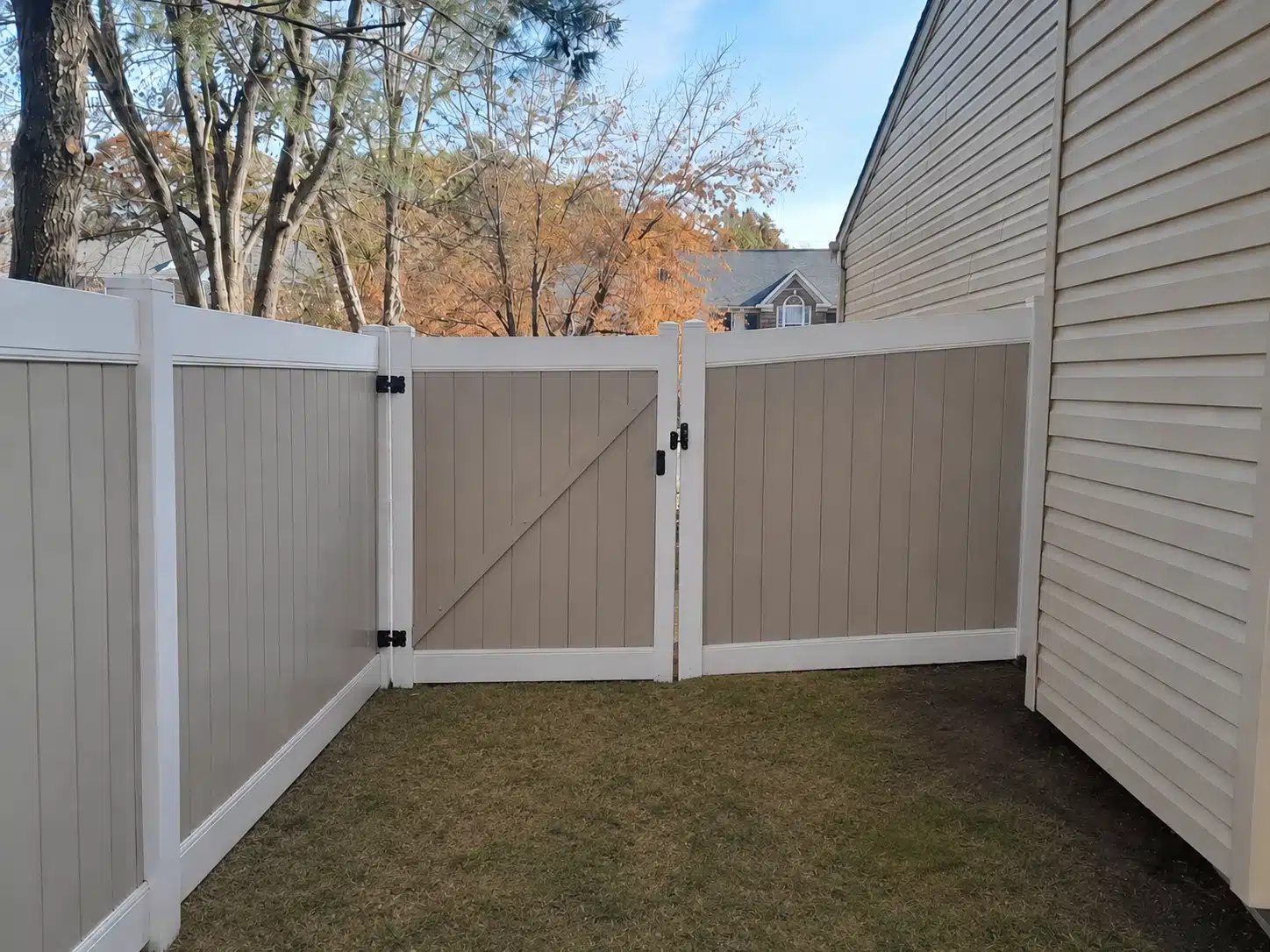 Tan and white vinyl privacy fence with a gated backyard entrance beside a home in Odenton, MD.