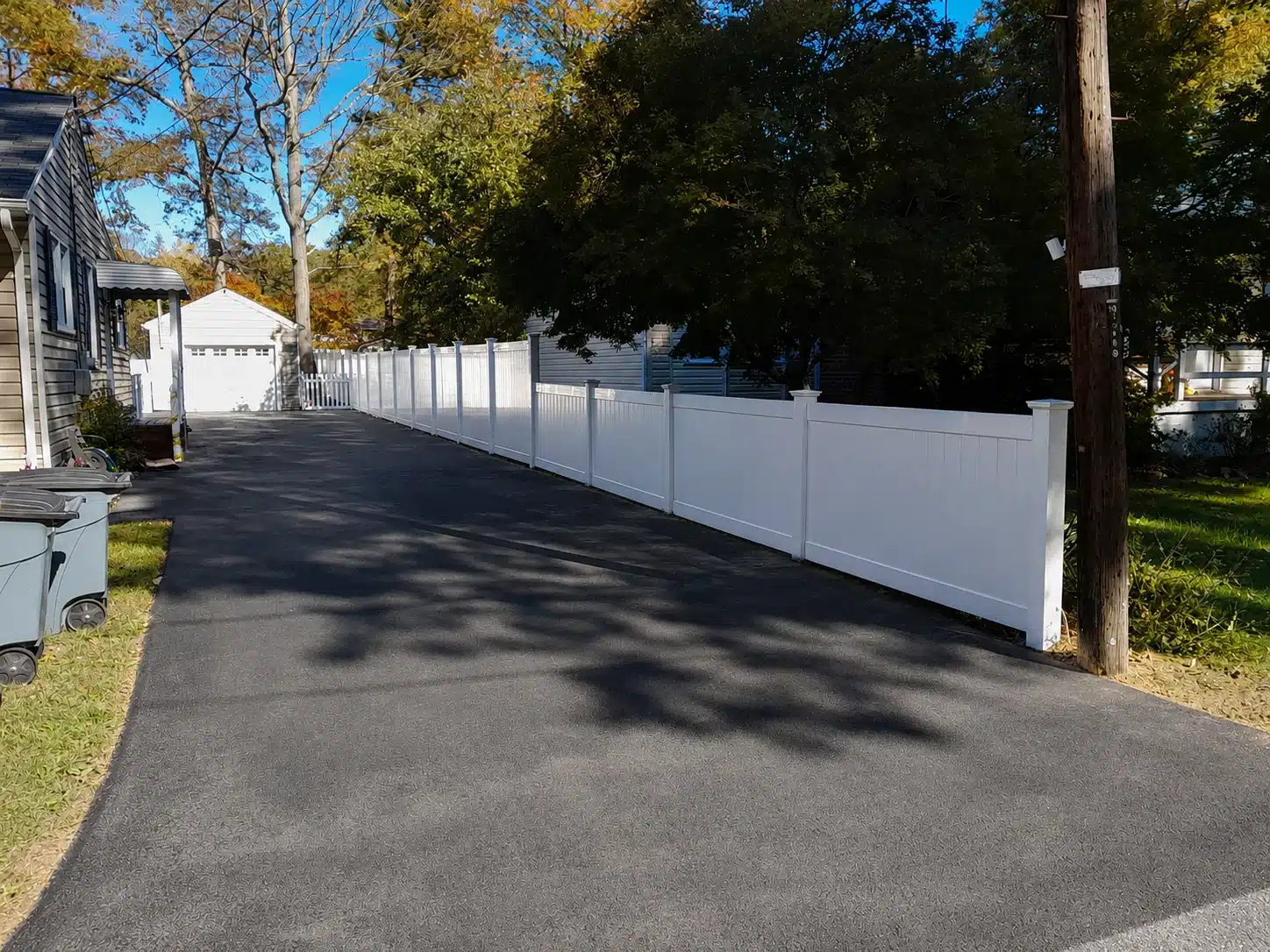 White full-privacy vinyl fence installed beside a residential driveway in Severna Park, MD.