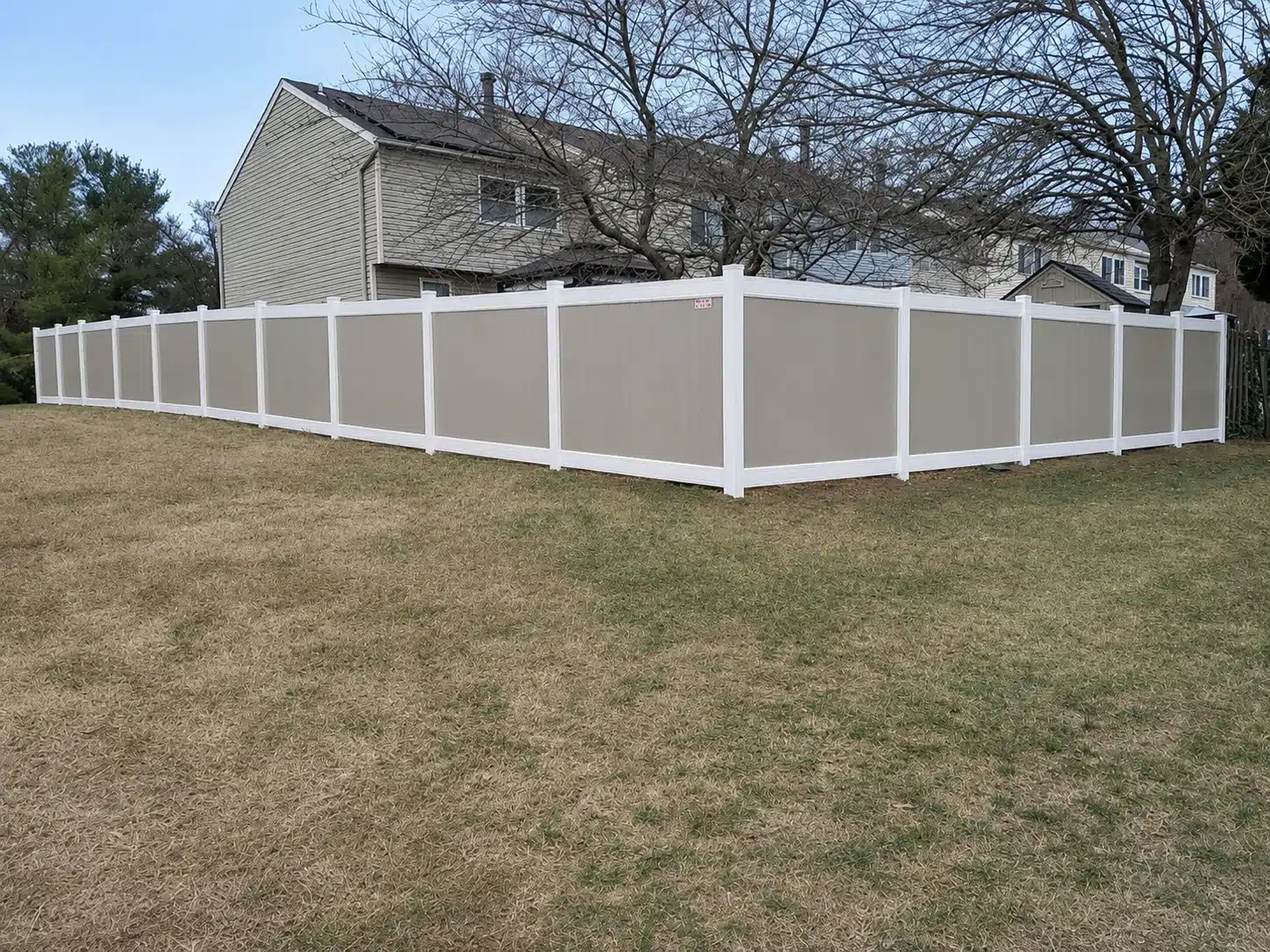 Two-tone tan and white full-privacy vinyl fence enclosing a residential yard in Severna Park, MD.