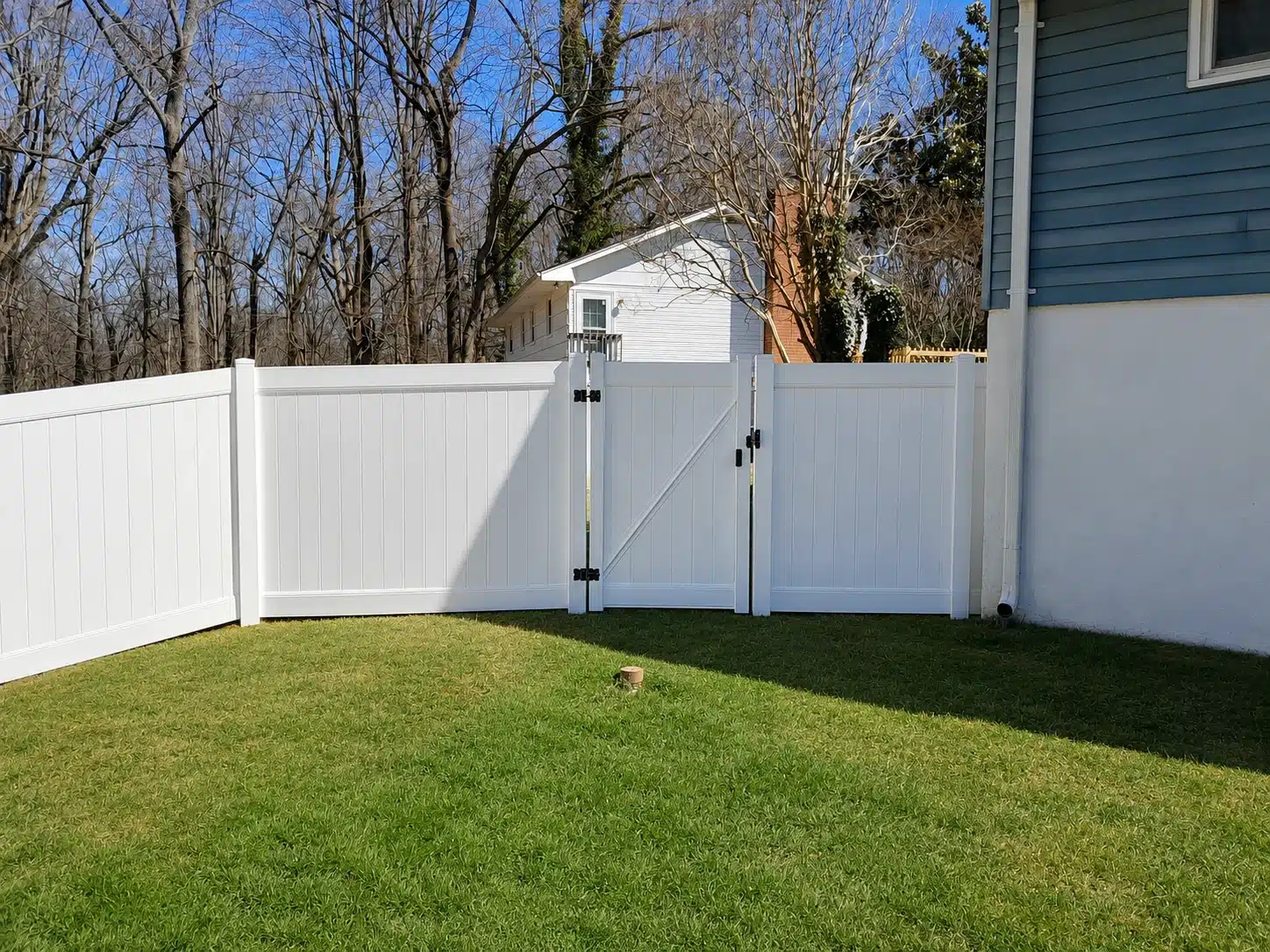 White vinyl privacy fence with double gates installed beside a home in Pasadena, MD.