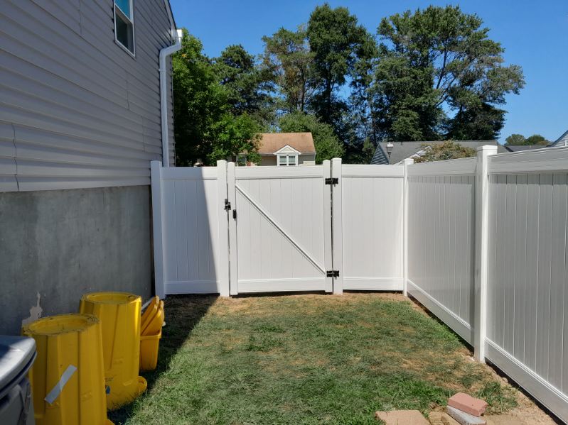 White vinyl fence with gate enclosing a Maryland side yard beside a house