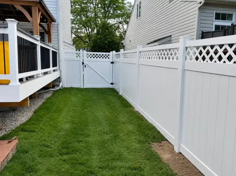 White vinyl lattice-top privacy fence with a double gate installed beside a residential deck in Pasadena, MD.