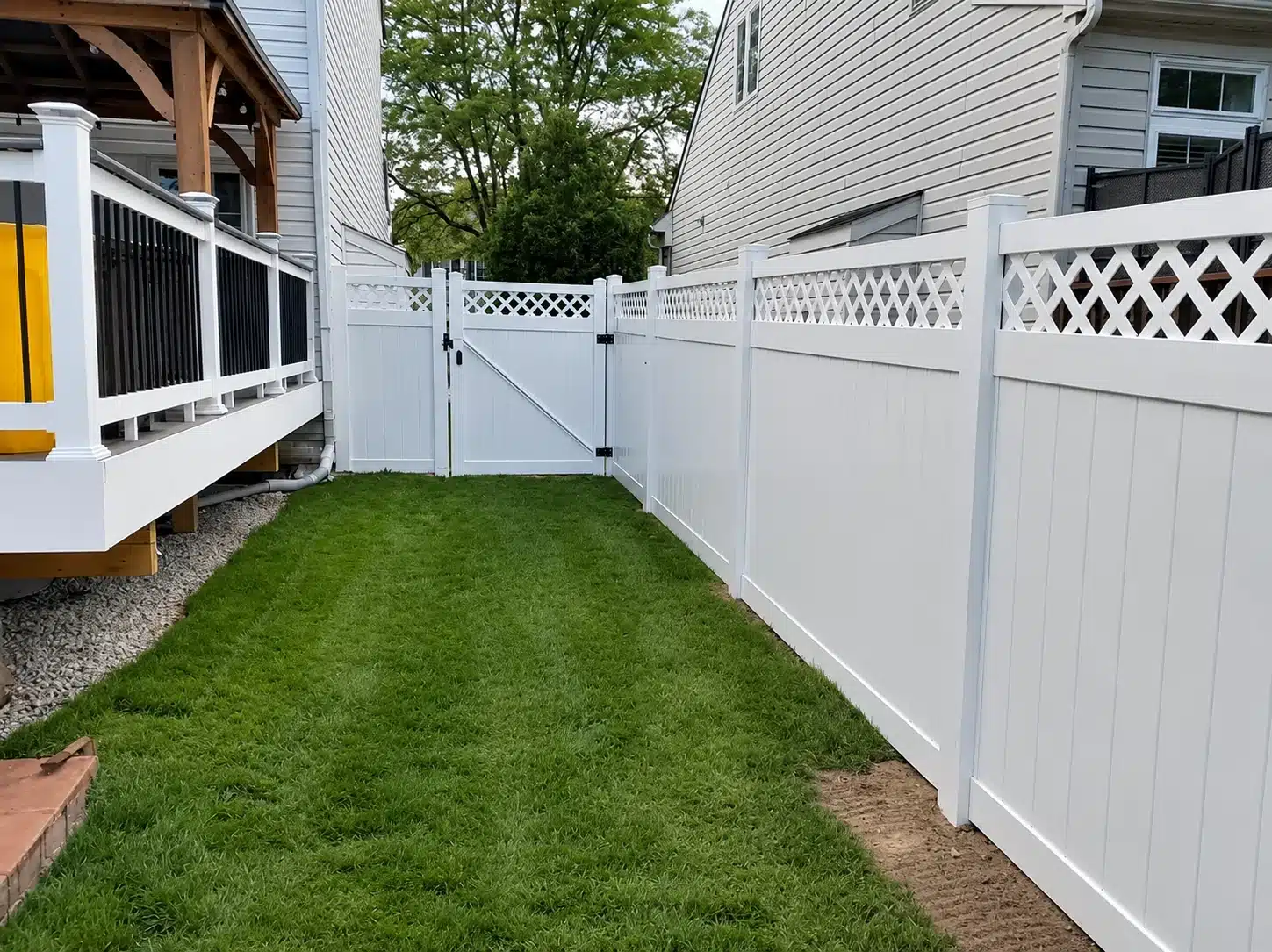 White vinyl lattice-top privacy fence with a double gate installed beside a residential deck in Pasadena, MD.