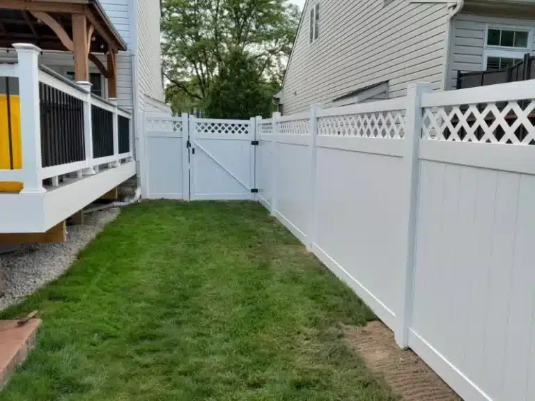 White vinyl lattice-top privacy fence with a double gate installed beside a residential deck in Pasadena, MD.