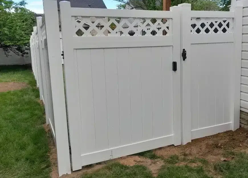 White vinyl privacy fence with a lattice-top gate installed along the side yard of a Pasadena, MD home.