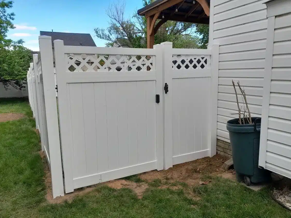 White vinyl privacy fence with a lattice-top gate installed along the side yard of a Pasadena, MD home.