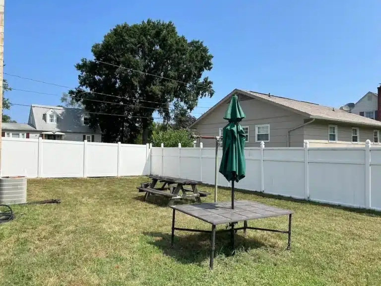 White vinyl privacy fence enclosing a backyard patio area with outdoor furniture.