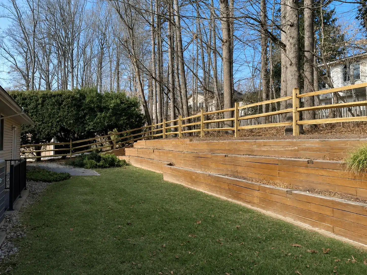 Split rail wood fence installed above a landscaped retaining wall in Severna Park, MD.